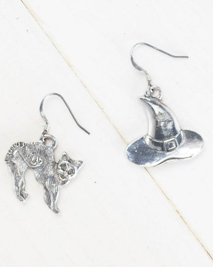 handcrafted pewter witch hat earring, featuring a small stamped star on the hat and a handcrafted pewter cat earring with detailed fur and an arched back, evoking a spooked stance, against a plain white background