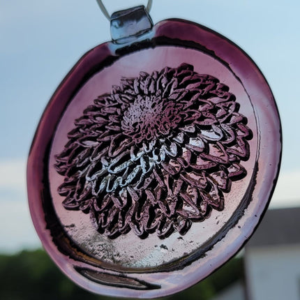 Glass suncatcher with a chrysanthemum flower design shown in light purple to better see the design.