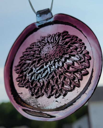 Glass suncatcher with a chrysanthemum flower design shown in light purple to better see the design.