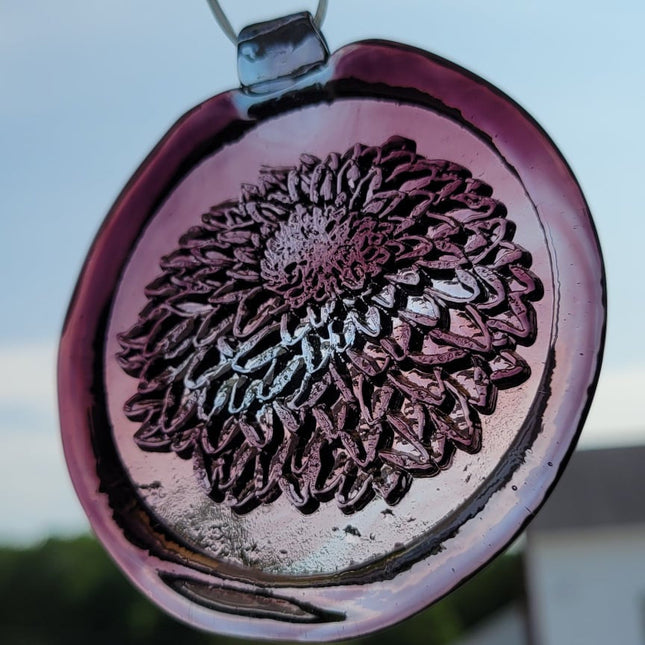 Glass suncatcher with a chrysanthemum flower design shown in light purple to better see the design.