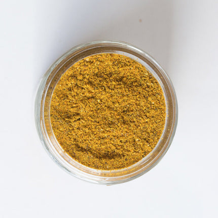 a top down view of an open jar of the comfort curry showing the rich, golden yellow hue of the spice blend