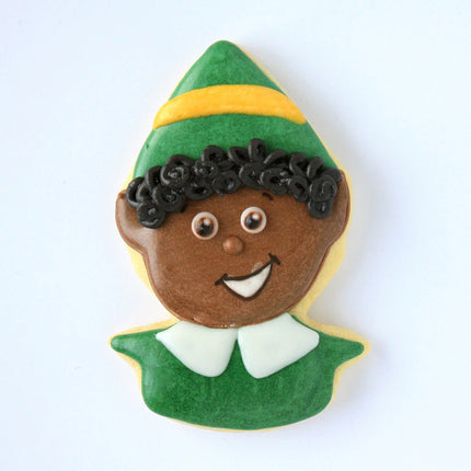 a fully decorated cookie in the shape of an elf's head with a pointed hat iced with green icing and a yellow brim on the hat, a smiling elf face with deep skin tone, and a white pointed collar on a green shirt