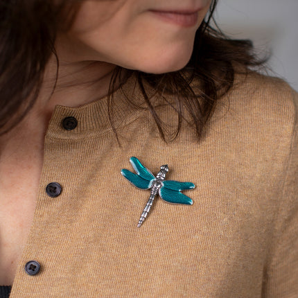 a close up of a model wearing a camel-colored sweater adorned with the dragonfly brooch