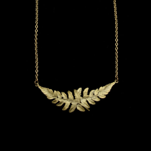 a close up of a delicate chain with a pendant featuring two overlapping fern sprigs cast in bronze with a delicate green patina