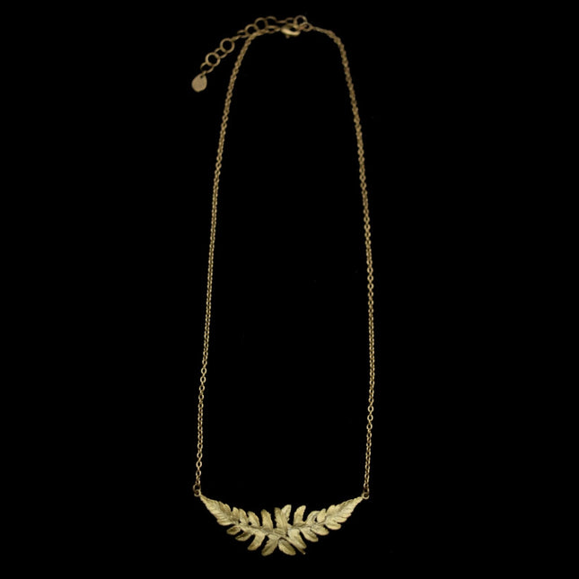 a full-length view of a delicate chain with a pendant featuring two overlapping fern sprigs cast in bronze with a delicate green patina
