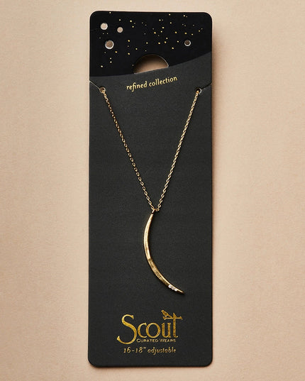 a slender gold pendant in the shape of a slice of the moon in its gibbous phase with 3 mini CZ stones on the bottom curve on a black card that serves as its packaging and shows more of the chain length