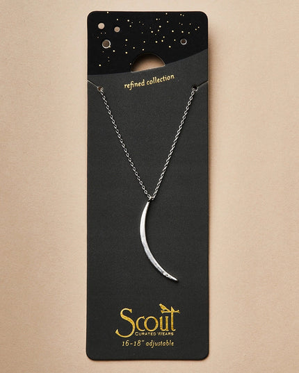 a slender silver pendant in the shape of a slice of the moon in its gibbous phase with 3 mini CZ stones on the bottom curve on a black card that serves as its packaging and shows more of the chain length