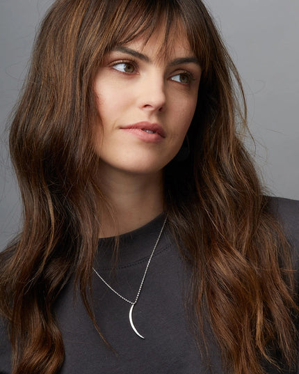 the silver gibbous slice necklace on a model showing that the chain length falls just below the collarbone