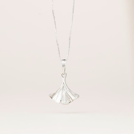an intricately detailed pewter ginkgo leaf shaped pendant hanging from a silver chain