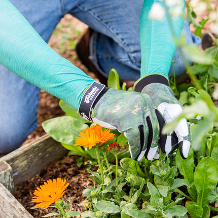 a close up of a model's hands in the garden with the heather green protection sleeves on their arms