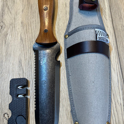 Essential Hori Hori knife shown side by side with its sheath and sharpener - side one of knife