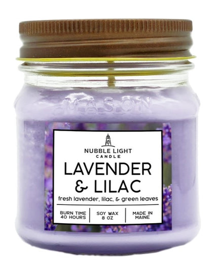 a candle in a clear glass mason jar with light purple wax and a label that reads "Lilac & Lavender" against a white background