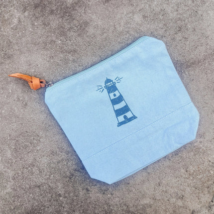 Light blue pouch with a lighthouse design on a concrete surface