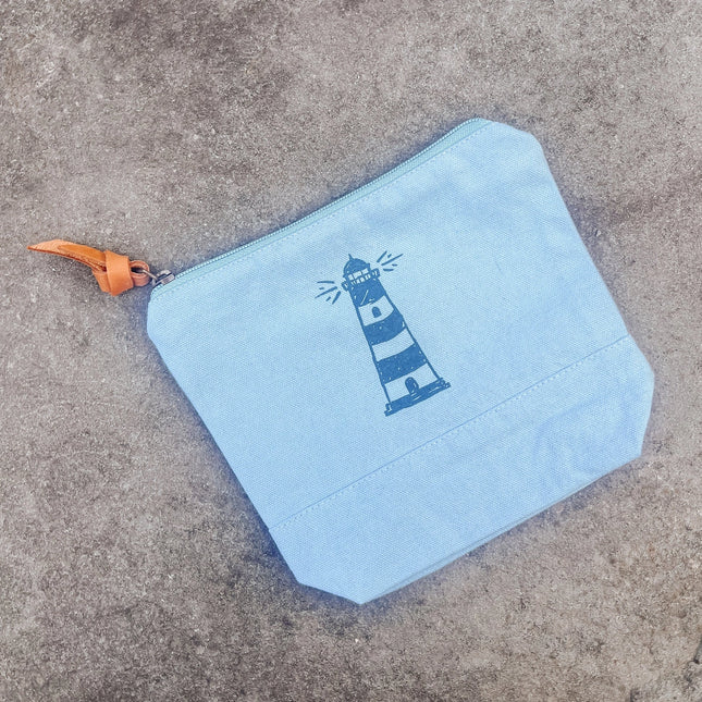 Light blue pouch with a lighthouse design on a concrete surface