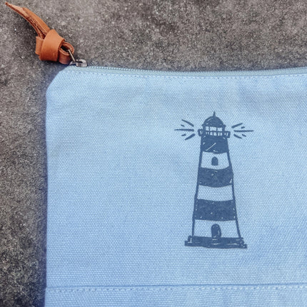 Light blue pouch with a lighthouse design on a textured surface