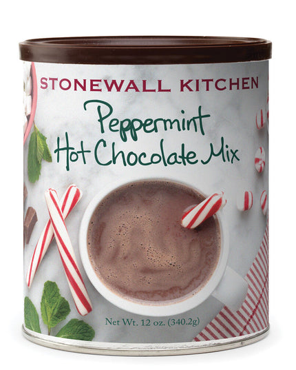 a can of peppermint hot chocolate mix with an image on the can of a marble countertop and overhead view of a white mug of hot chocolate with red and white striped candy canes around it