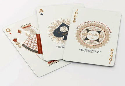 a selection of cards from the deck fanned on a white table showing the modern and minimal design of the suits and joker card
