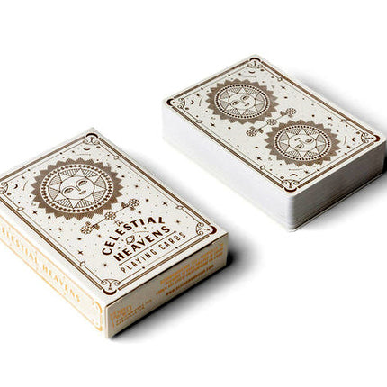 The celestial heavens playing cards deck and box side by side with celestial artwork that includes two radiant suns with faces, surrounded by minimalistic stars, crescent moons, and tiny planets