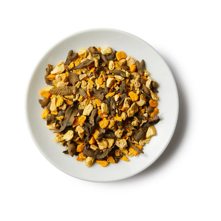 a small white round dish containing a mound of sailor's cure all loose leaf tea showing the strong yellow turmeric ingredients, seaweed, and others
