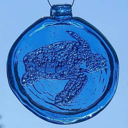 a round blue glass sun catcher with relief image of a sea turtle