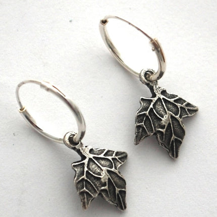 close up of silver maple hoop earrings on a white surface