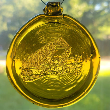 Yellow glass suncatcher with a covered bridge design.