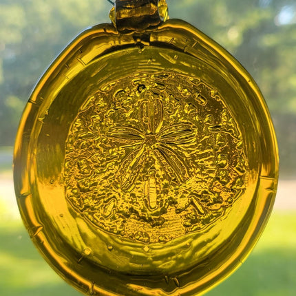 Yellow handmade glass suncatcher with a sand dollar design.