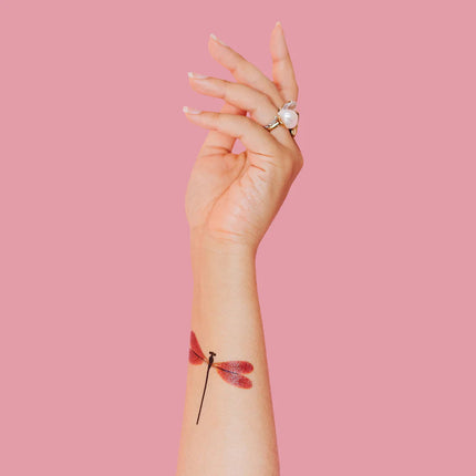 a model's arm pointed upward with the amber damselfly tattoo applied to the inner forearm
