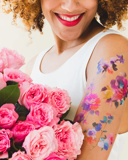 a model holding a bouquet of pink roses with the tattoos applied to her upper arm