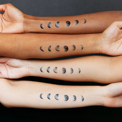 four arms of varying skin tones with the moon phase tattoos applied to their skin to show how the tattoos appear on various skin tones