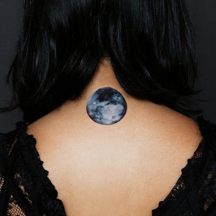 The back of a model's neck showing the Full Moon phase tattoo applied at the nape of the neck