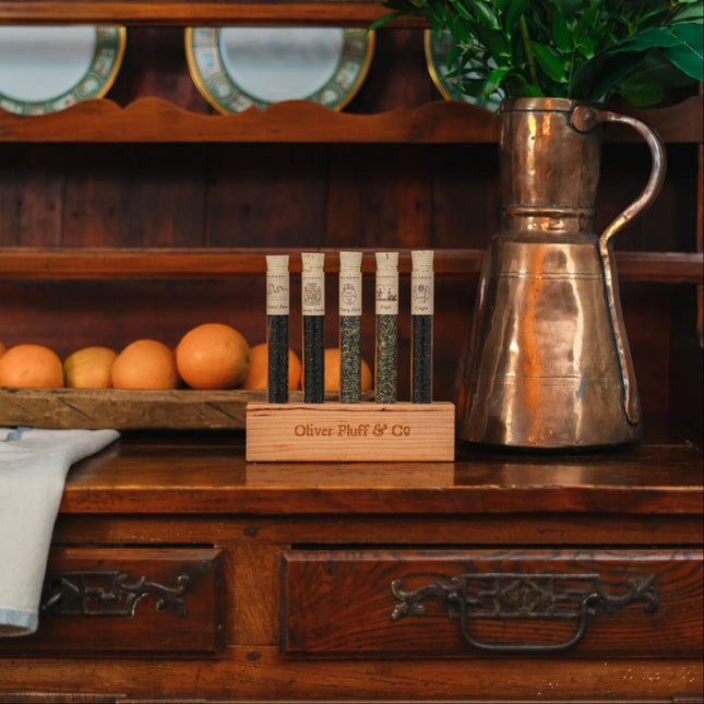 Copper pitcher and Teas of the Boston Tea Party block holder on a wooden surface with oranges in the background.