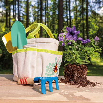 kids garden tote and tools on a table outdoors next to some flowers ready to be potted