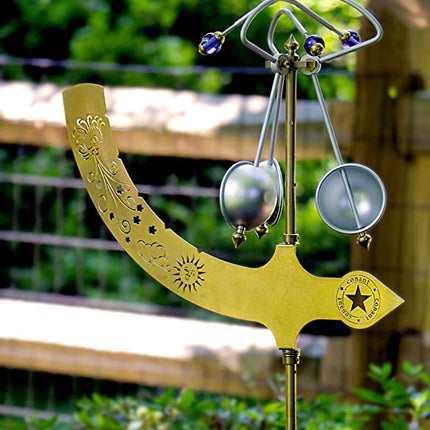 an outdoor close up of  A decorative wind chime featuring a copper-colored tree of life design with dangling chimes that are wind propelled.